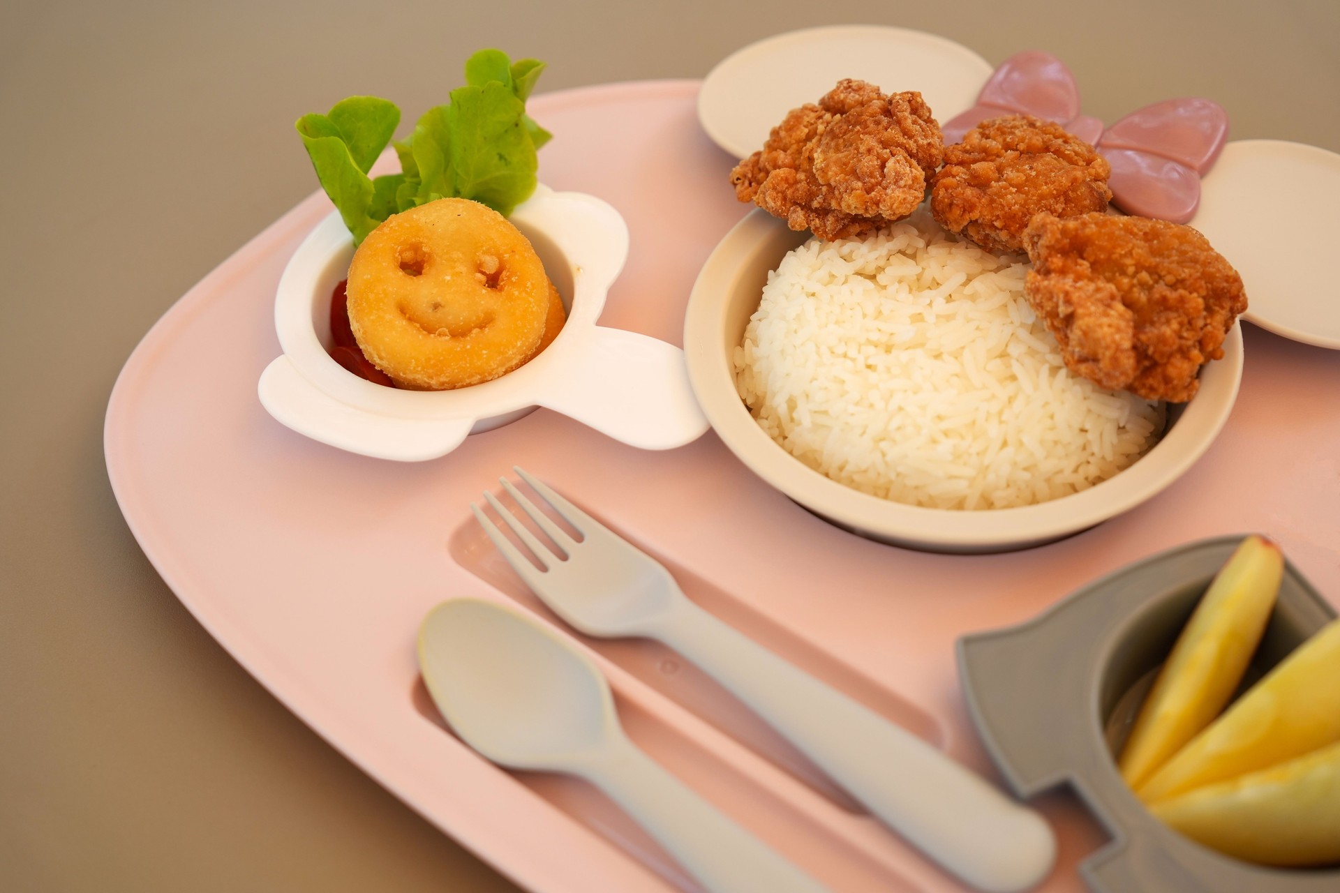 Top view close up meal tray for Kid with chicken on top of rice with smile potato fried so creative dish for hard eatting kids decorate food in section with cute spoon and fork.